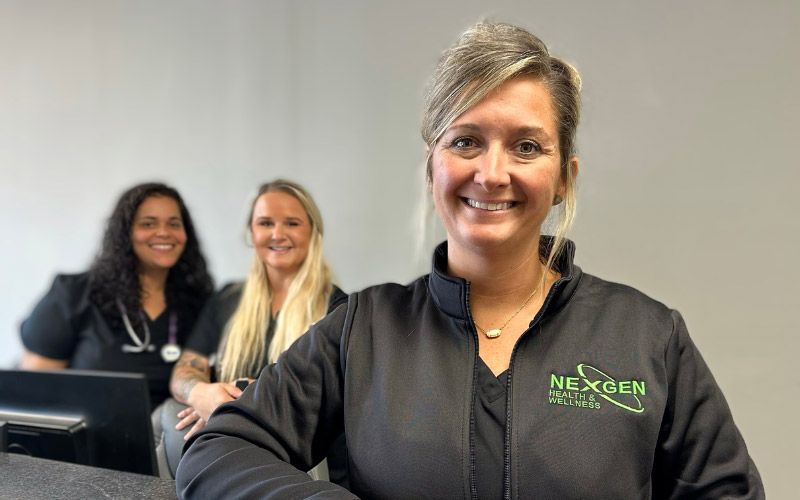 Three female staff members promoting weight loss products at NexGen.