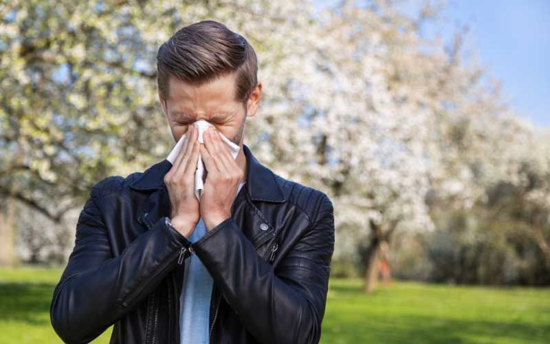Man sneezing due to allergies.