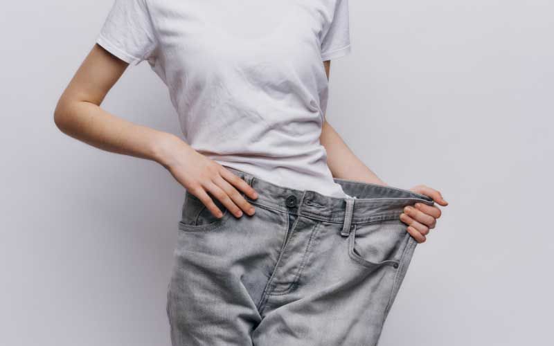 Person that has lost weight showing off their pants.