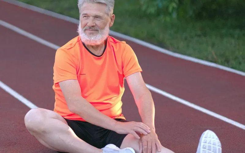 Men's health and wellness - man stretching legs on running track.